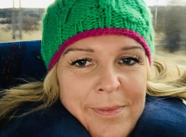 Woman with blond hair wearing a bright green wool hat with a red trim band.