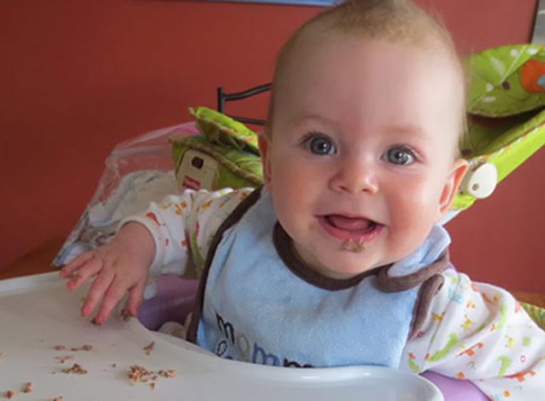 Baby eating solid foods in high chair.