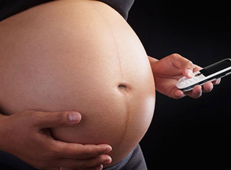 Pregnant person holding a cell phone.