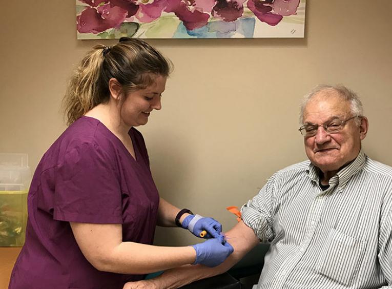 A woman draws blood from an elderly man. 