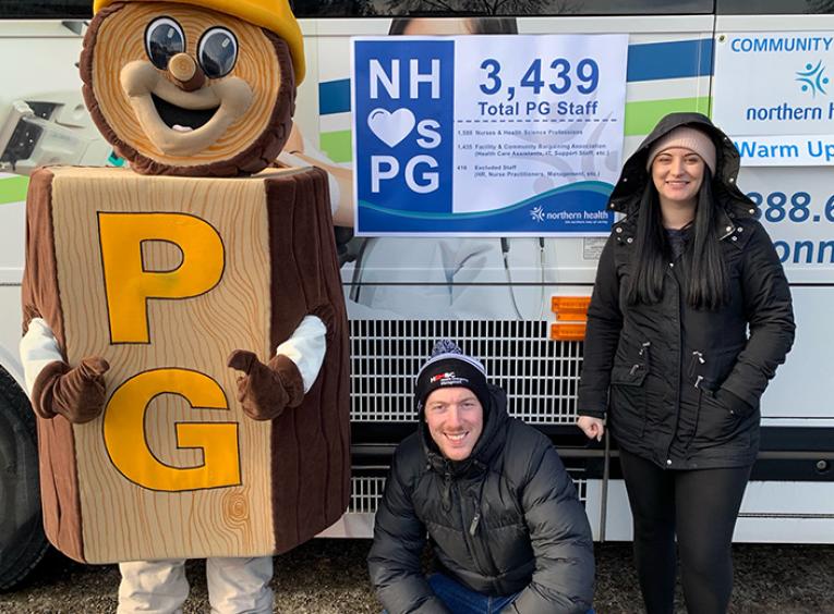 The Mr. PG mascot stands with a crouching man and a standing woman next to the NH Connections bus.