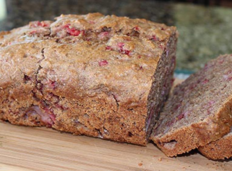 Loaf of strawberry bread sliced on cutting board