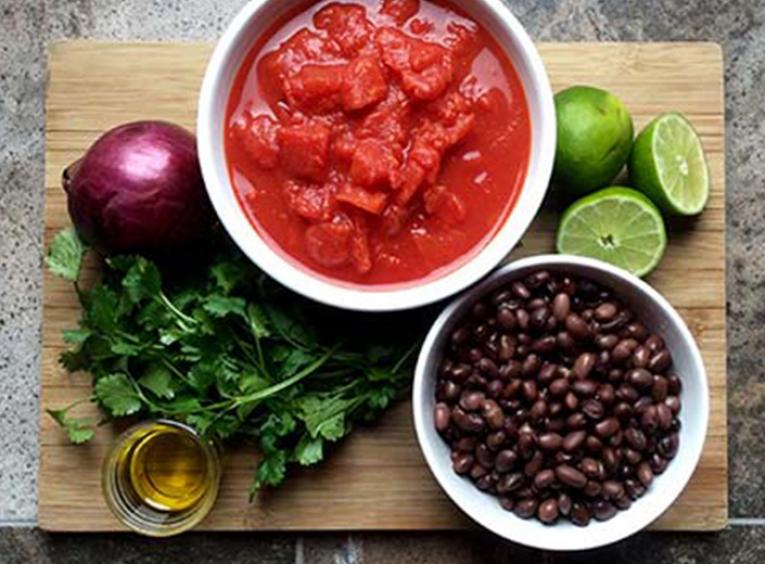 Ingredients to make black bean salsa displayed on a cutting board
