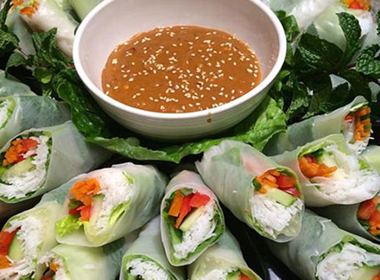 Fresh spring rolls stacked on a plate with dip