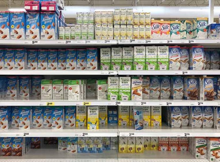 Cartons of plant-based beverages line section of the grocery store.