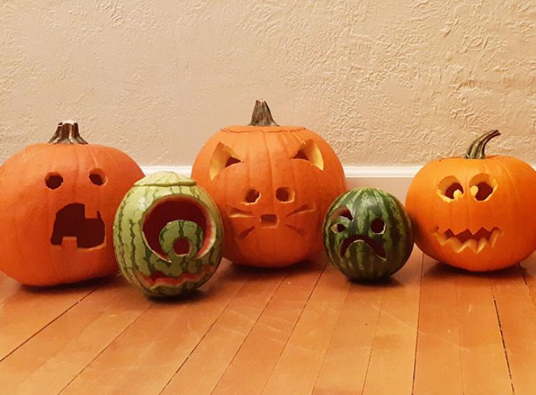 A row of carved jack-o-lanterns sitting on the floor.
