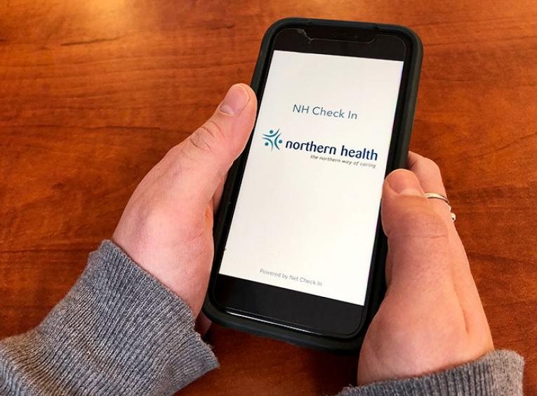 Hands hold cell phone with NH Check In application open on the screen