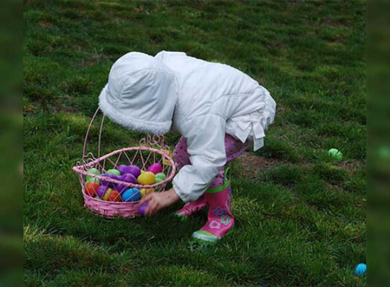 Child picking up coloured Easter eggs.