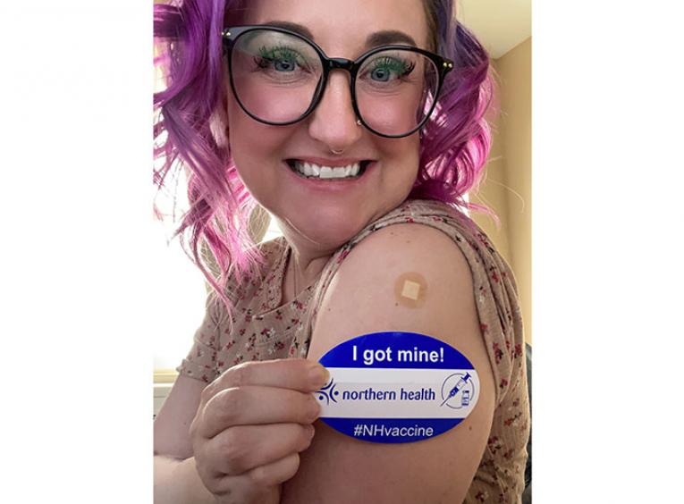 Woman shows off a sticker that says she got her vaccine