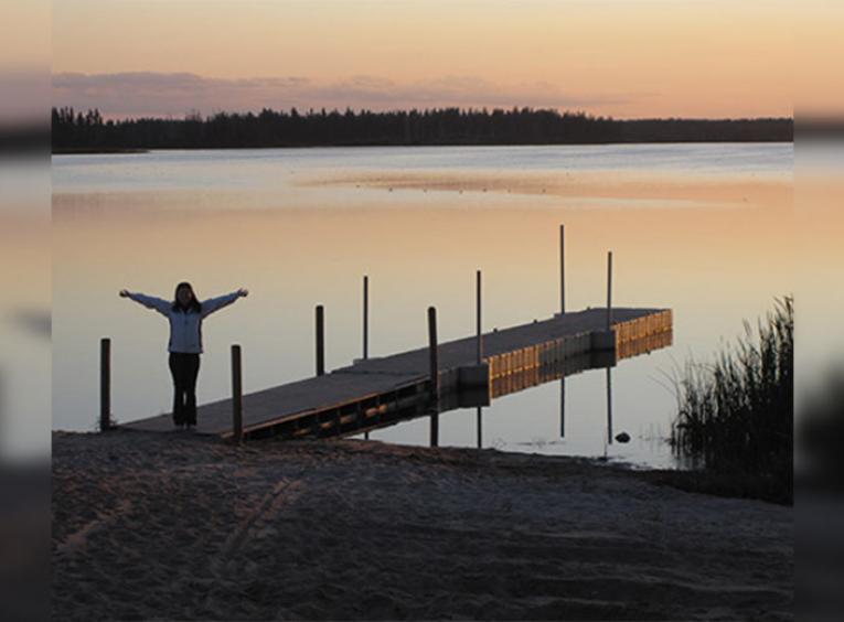 Woman standing on a dock in the sunset.