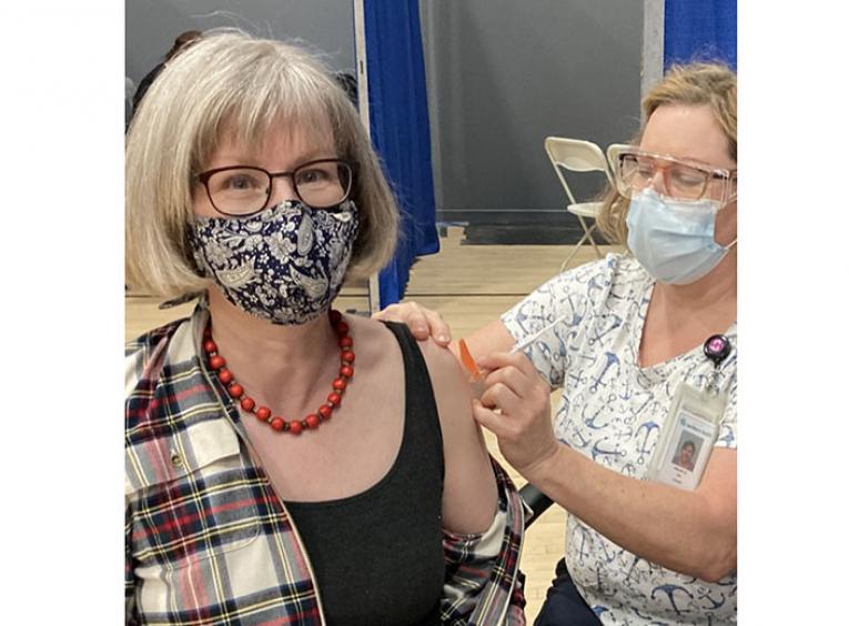 Woman wearing a mask receives a vaccine from a nurse