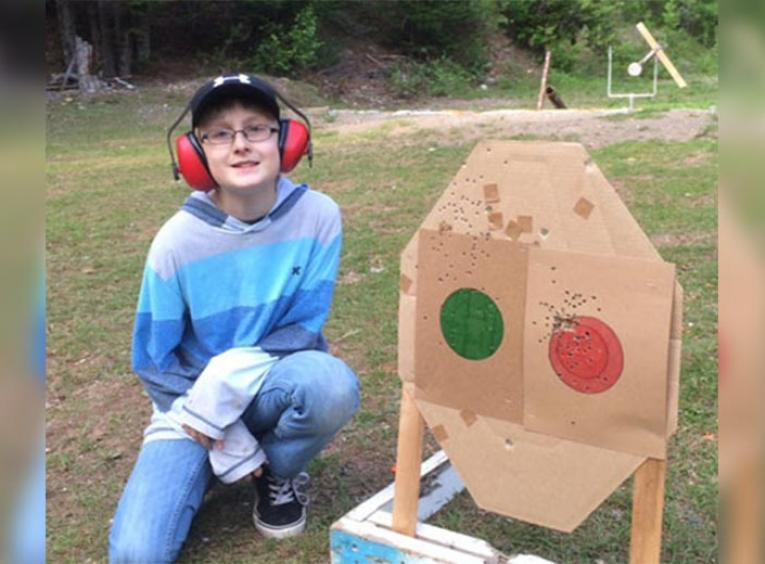 Boy sitting beside a shooting target