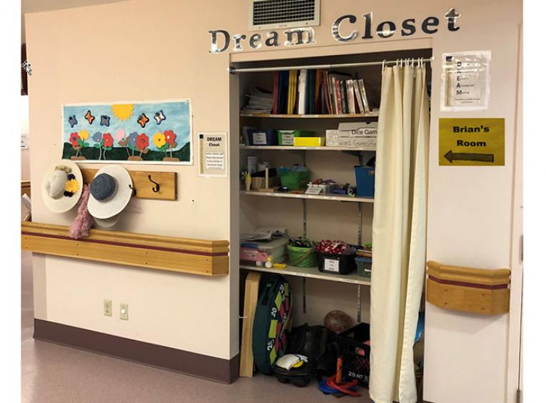 A closet in a long term care hallway with resources for crafts, hats and signage for seniors