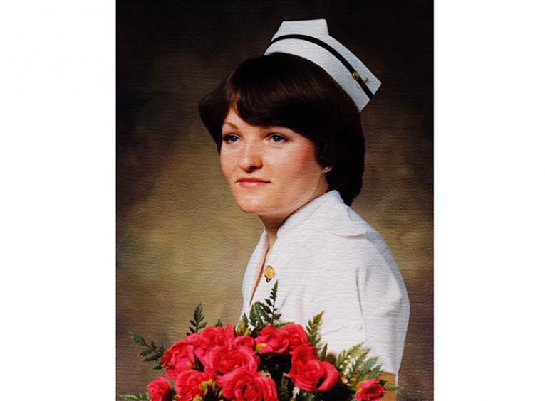 Older photo of a graduating nurse holding a bouquet of roses