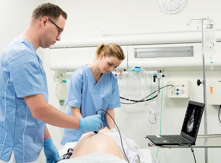 two health care professionals using mannequin for medical simulation