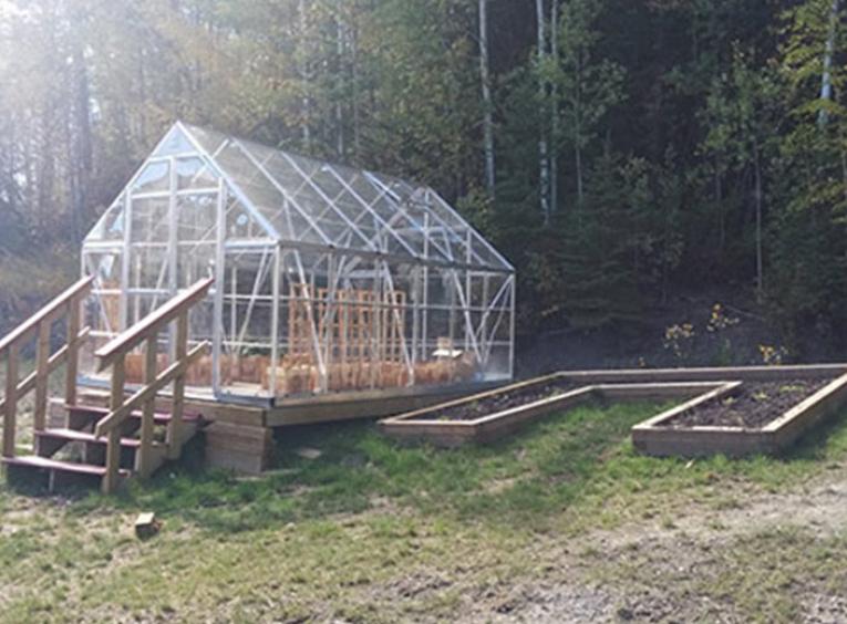 Greenhouse with stairs and a raised garden bed on the right