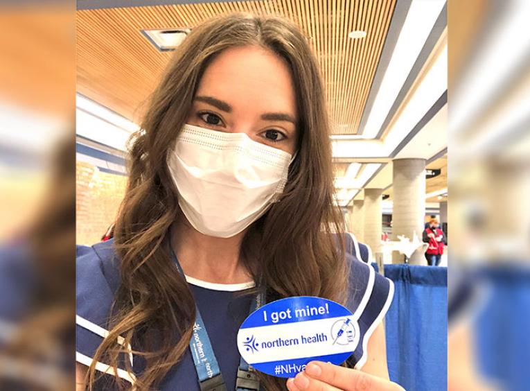 Woman in a mask shows off a get vaccinated sticker