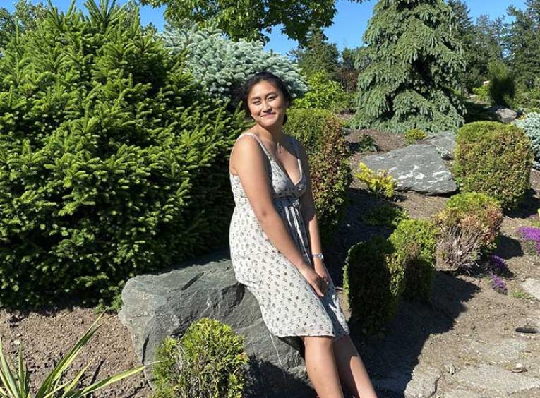 Woman sits on rock in garden