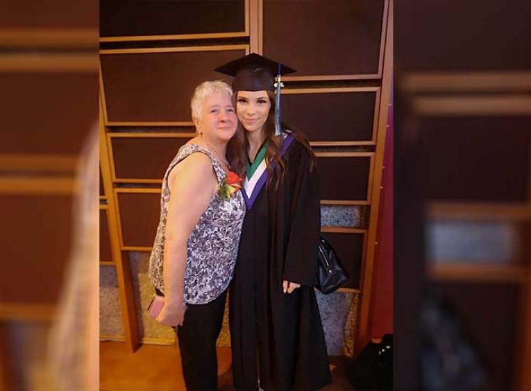 Adella stand with her granddaughter Addie who is wearing a graduation cap and gown