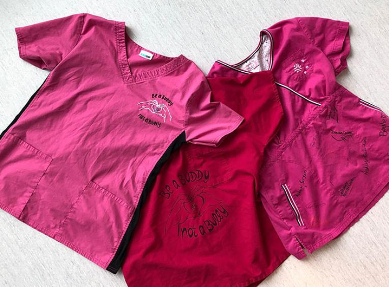 Three pink shirts with anti-bullying messages laid out on display