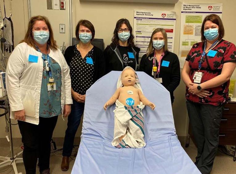 a group of health care professionals pose with the sim baby 
