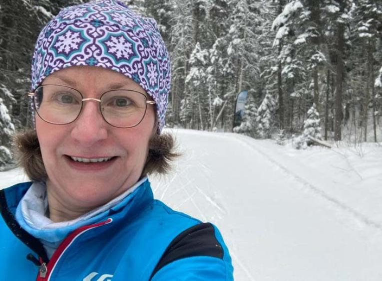 a woman with grey hair wearing a toque takes a selfie with a snowy background