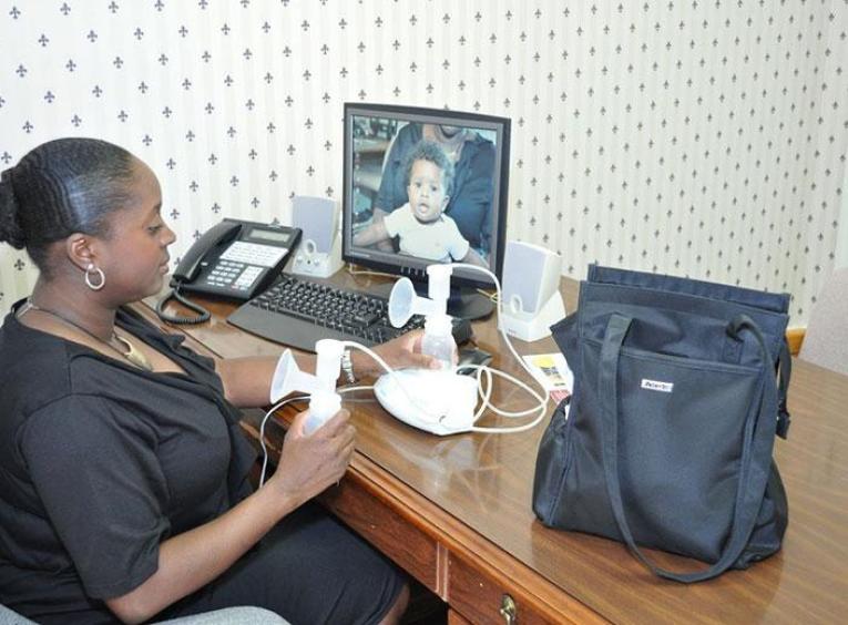 Woman sits at a desk pumping breast milk.