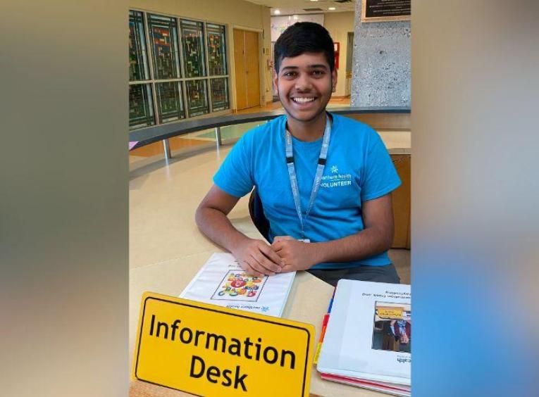 Aarya in a blue shirt sitting at the information desk ready to help