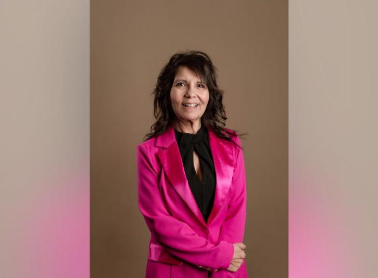 Patricia stands in a pink blazer and black top.