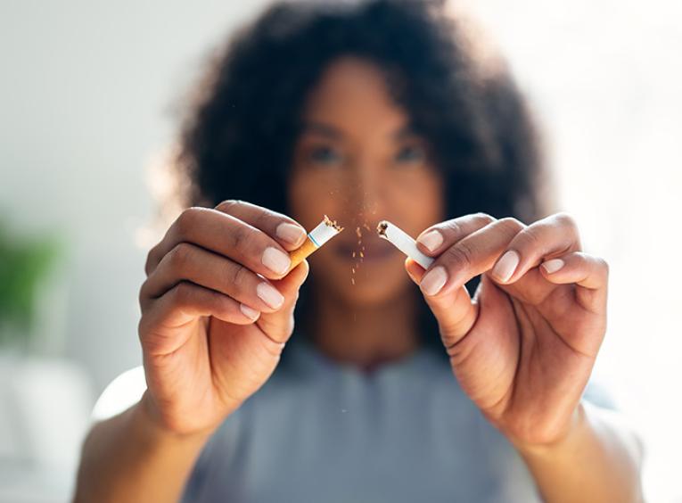 A woman breaks a cigarette in half