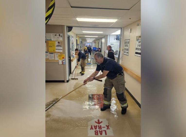 Fire fighters mop and push water down the hallways of the Stuart Lake Hospital during clean up efforts