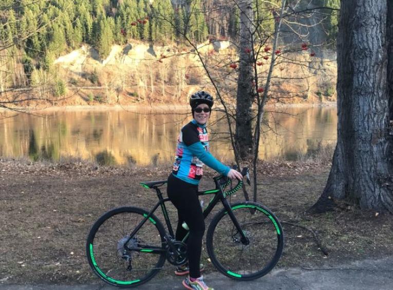 Gloria standing with her bike with the Fraser river in the background