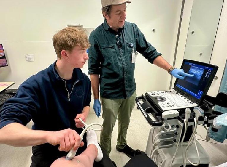 Dr. Tracy Morton and his son, Lief, scanning a patient’s knee bedside to prepare for an injection.
