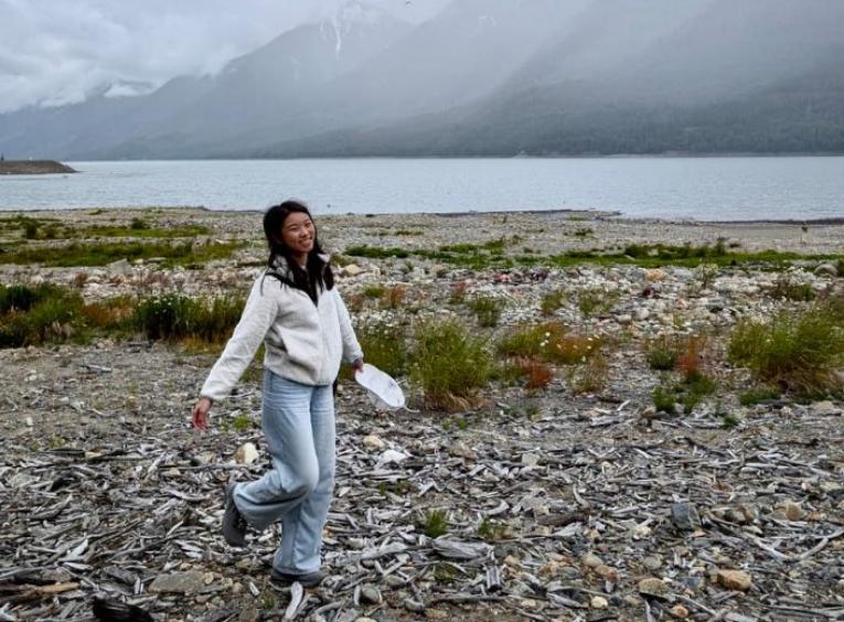 Tiffannie walking over white beach wood set against a lake and mountains in the background