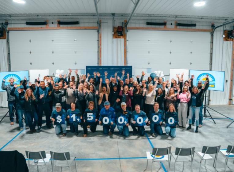 Group of people stand behind sign that reads 1.5 million dollars