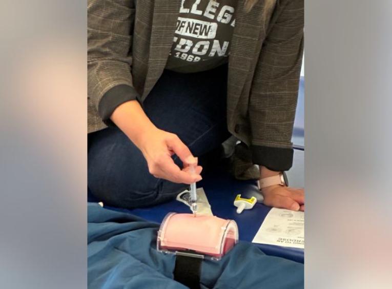 a student holding a syringe while working ona  prosthetic body part