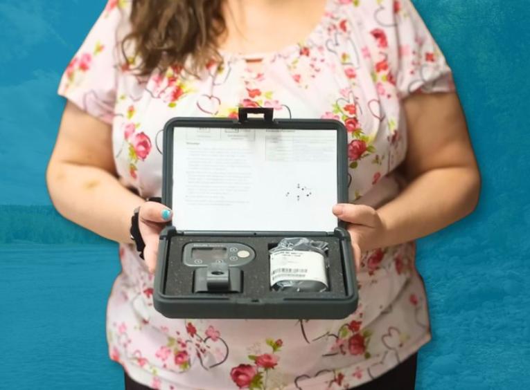Person stands holding a holter monitor