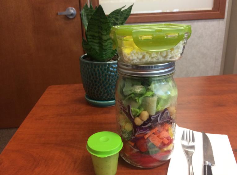 A layered salad in a mason jar, showing multiple layers of vegetables throughout the jar.