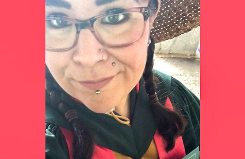 Jessie on convocation day, wearing the robes of a Ph.D. and a traditional cedar hat, and holding her degree.