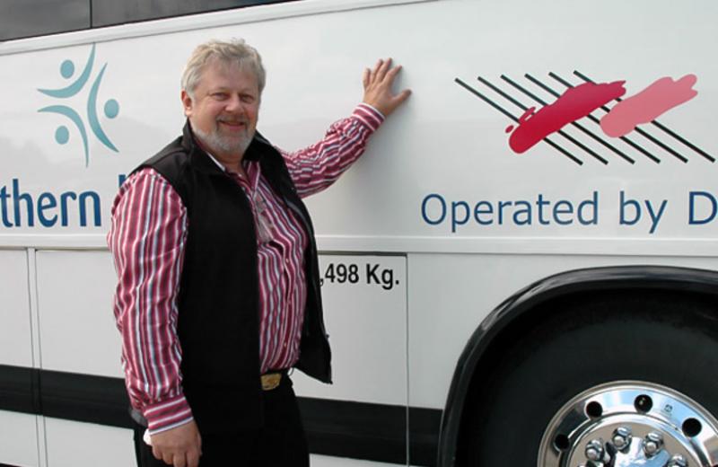 A man leans on an NH Connections bus.