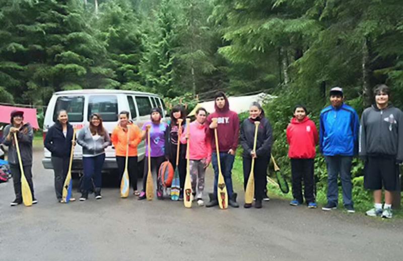 Youth group on forest roadside with paddles.