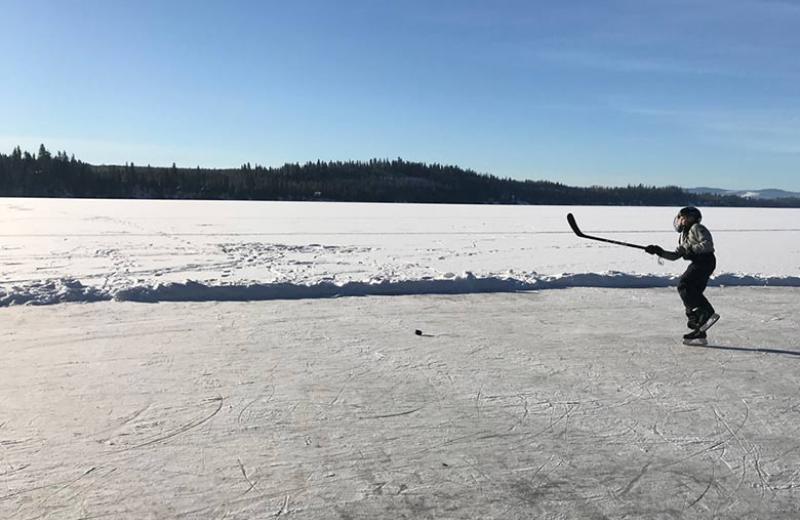 boy playing hockey on frozen lake.