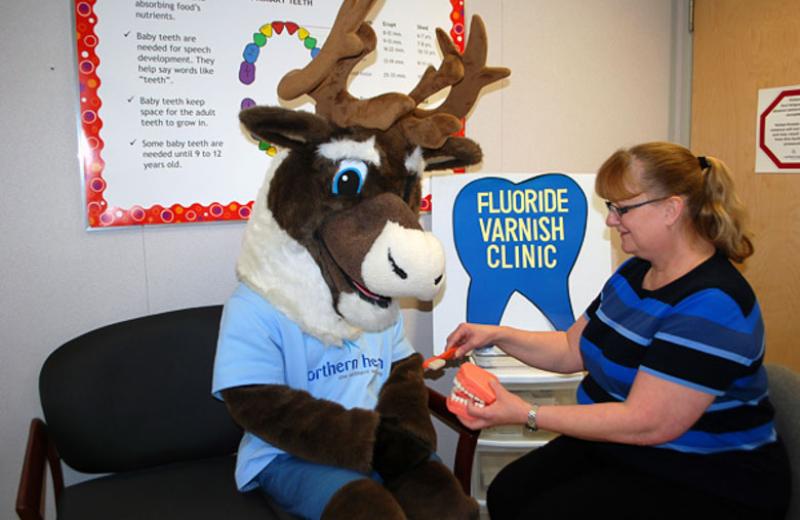 Spirit the Cariboo at a fluoride varnish clinic with an NH staff member.
