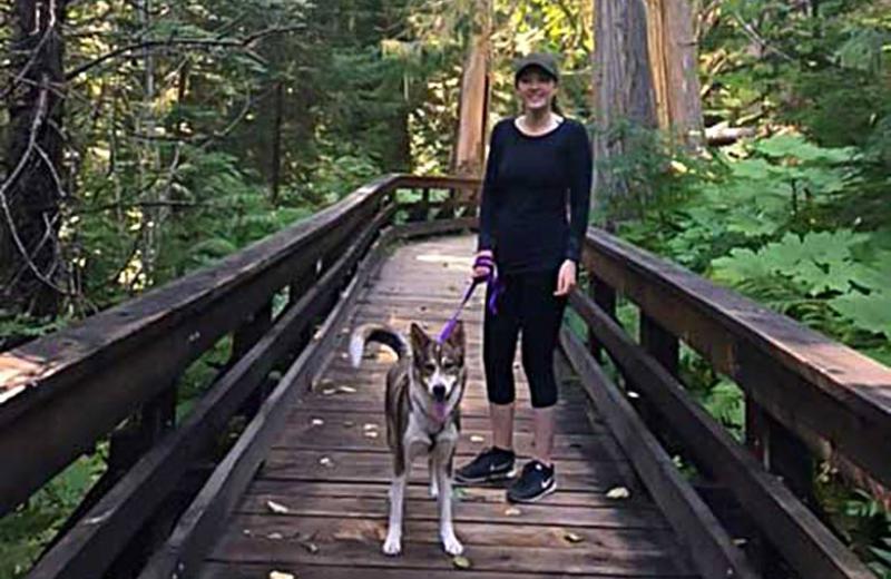Jaymee webster on a bridge in the woods with her dog.
