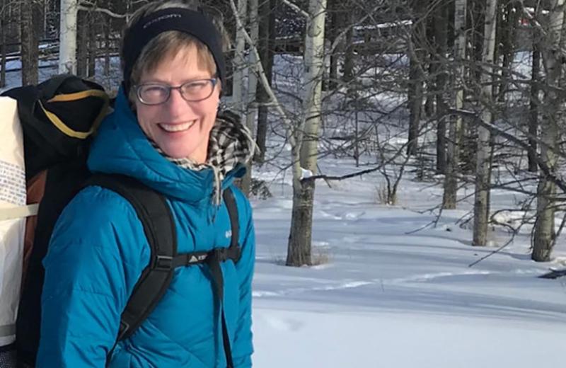 Woman on a trail hiking in snow during winter.