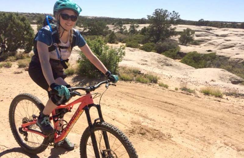 Woman riding a bike through a desert .