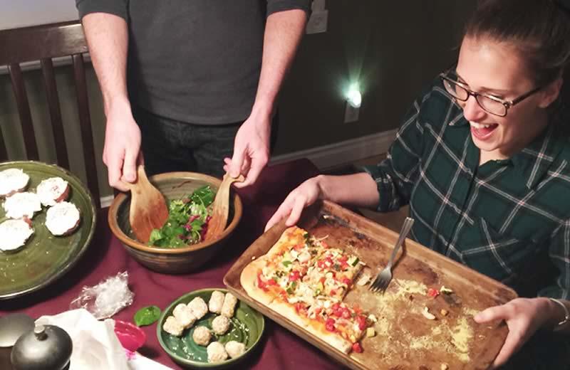 Two people at a table excited to eat pizza and salad.