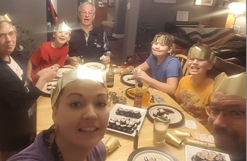 7 people around a dinner table wearing paper crowns.