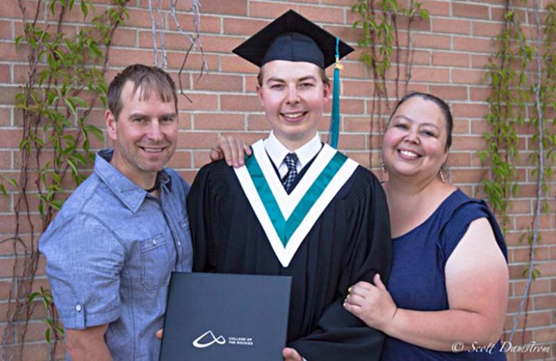 Man standing with his parents posing at graduation.