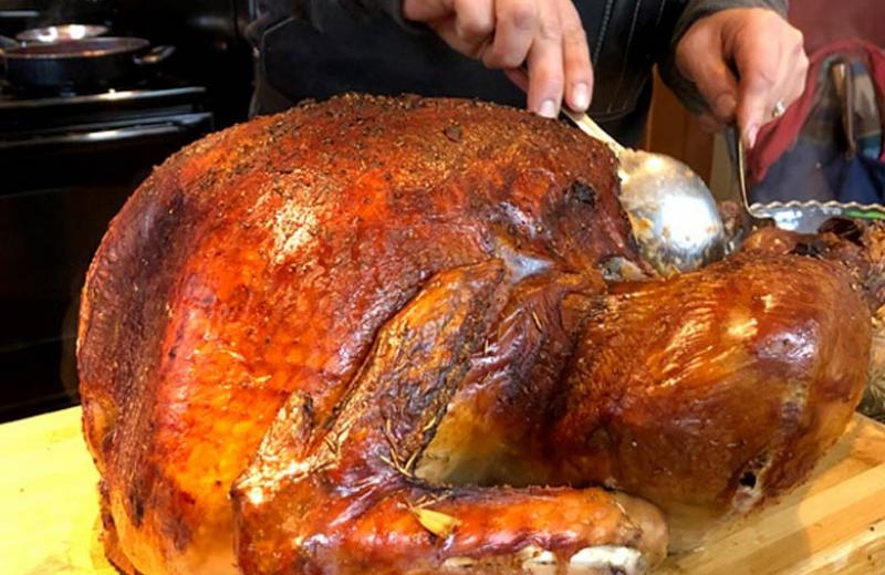 A man carves a turkey on a cutting board.